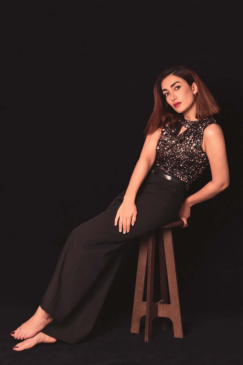 clothing woman in black keyhole sleeveless dress sitting on brown wooden stool apparel